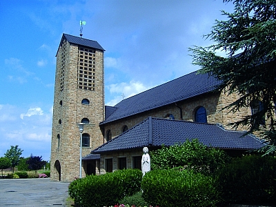 Außenansicht der Kirche St. Maria Himmelfahrt in Schlickelde mit Turm, Vorbau und Statue im Eingangsbereich