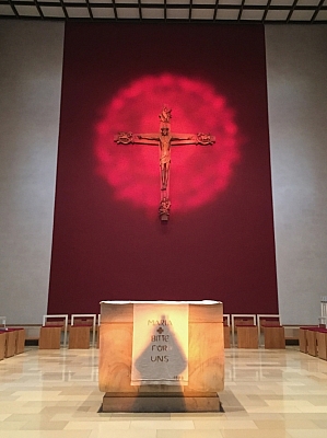 Moderner Altarraum mit Kreuz und rotem Hintergrund in der Pfarrkirche St. Mariä Himmelfahrt in Schlickelde