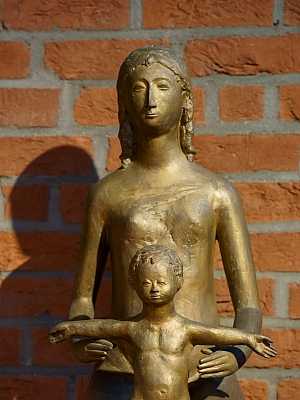 Moderne Bronzestatue mit Kind vor Backsteinwand in der Pfarrkirche St. Margaretha in Westerkappeln