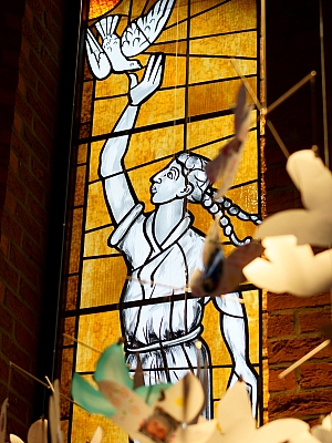 Glasfenster in der Pfarrkirche St. Margaretha in Westerkappeln mit Frauengestalt, die eine Taube in den Himmel entlässt – Symbol für Frieden und den Heiligen Geist